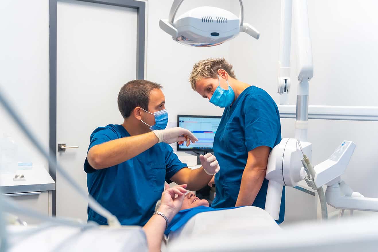 Dental clinic, dentist doctor and assistant examining the teeth of an elderly woman lying on the table