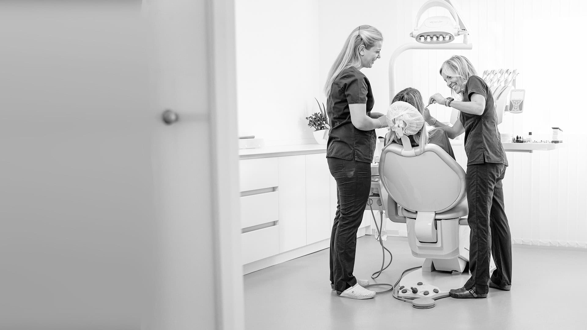 Two dental techs cleaning a woman's teeth