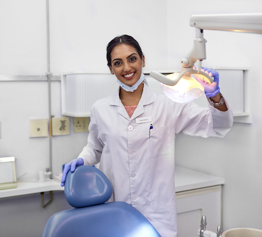 Portrait of a young female dentist standing alongside the dental chair in her office.